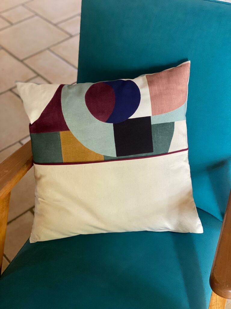 coussin fait sur-mesure posé sur un fauteuil bleu